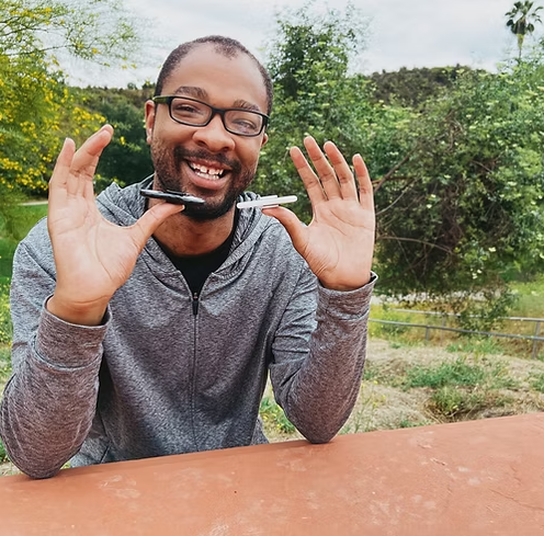 A Young Man Smiling While Playing With Fidget Spinners